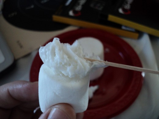 Use a nickel sized scoop of frosting on the bottom of the regular sized marshmallow and place it in top of the jumbo marshmallow.