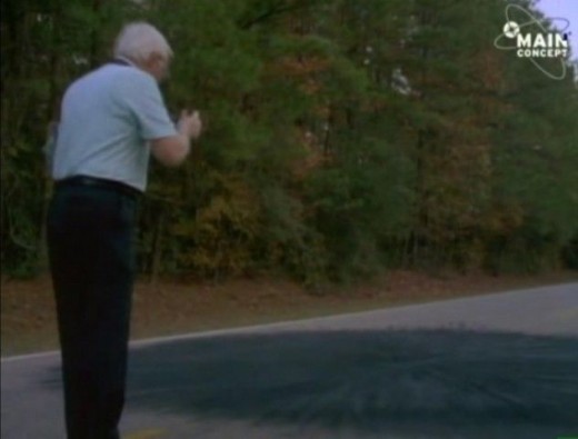 A photograph of an investigator investigating a scorch mark in the road where Cash and Landrum said the UFO hovered. 