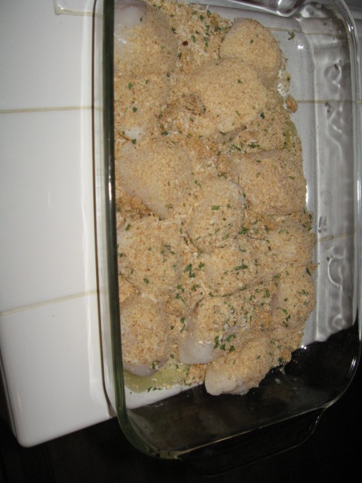 Scallops in baking dish with bread crumb mixture sprinkled and ready for oven.
