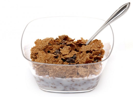 A bowl of Raisin Bran cereal shown in a clear plastic bowl and low-fat milk