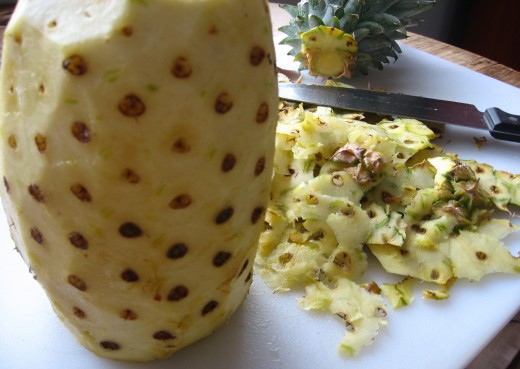 A fully-peeled pineapple with fruit still intact.