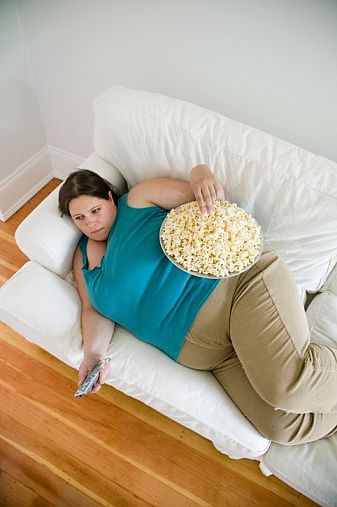 A fat woman watching TV while eating.