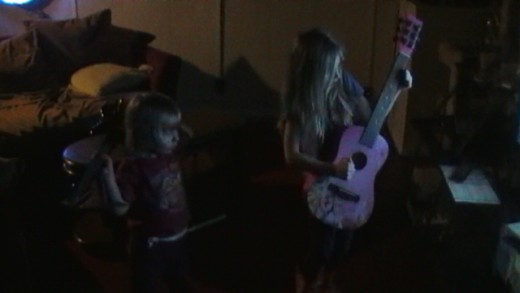 Motley Two dueling guitars. The youger shows her skills while playing rythm guitar behind her back.