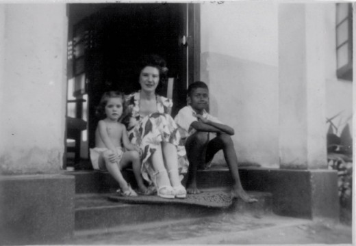 Mum and me sitting on the doorstep of our bungalow with a neighbour.
