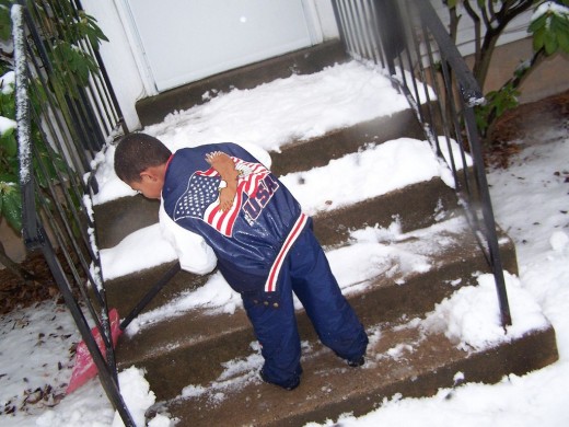 child clears snow from steps