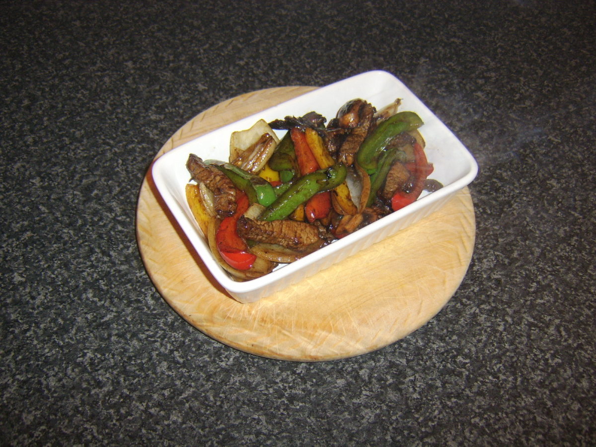 Stir fried steak and vegetables are added to a preheated serving dish