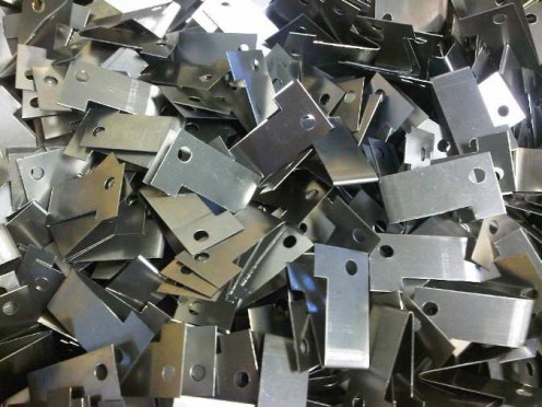 Spring stainless steel angle brackets used to hold lighting reflectors in place.  These parts have been produced from spring stainless steel coil, cut to size and then produced with simple fly press tooling. 