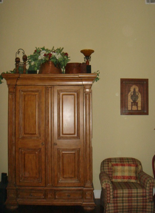 The scale of the chair and picture on the right are out of balance with the armoire.