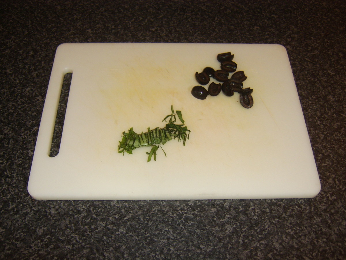 Roughly chopped basil and black olives garnish the dish for service