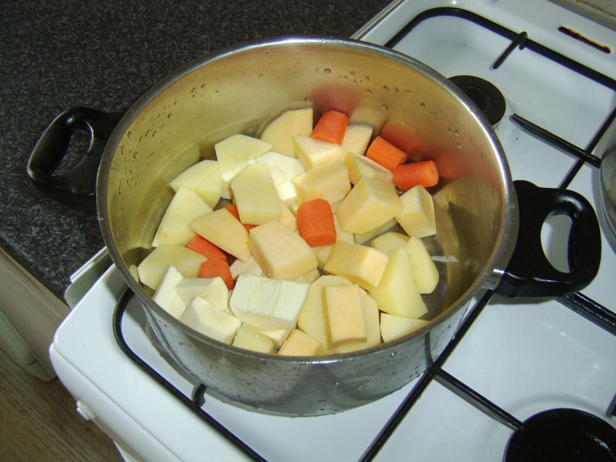 Chopped vegetables are added to a large stew pot