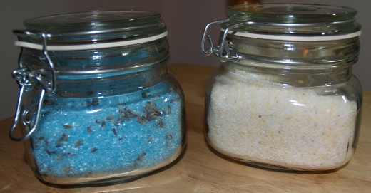 On the left are bath salts made with Epsom salts and dried lavender flowers, On the right are bath salts made wiith Dead Sea Salt and lemon esential oil.