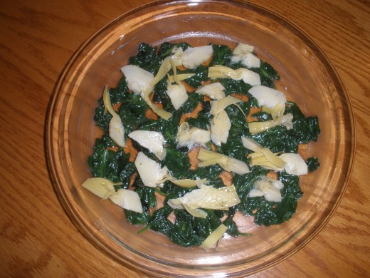 Artichoke heart slices on top of the spinach.