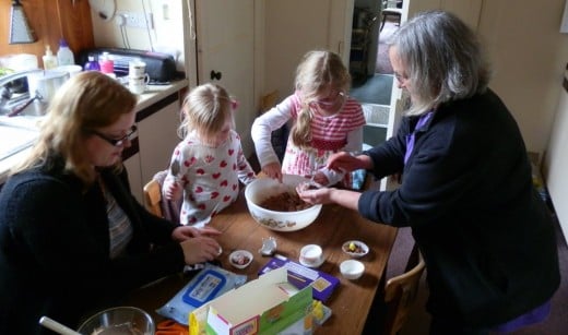Granny helps the kids fill the paper cases with the chocolate mixture