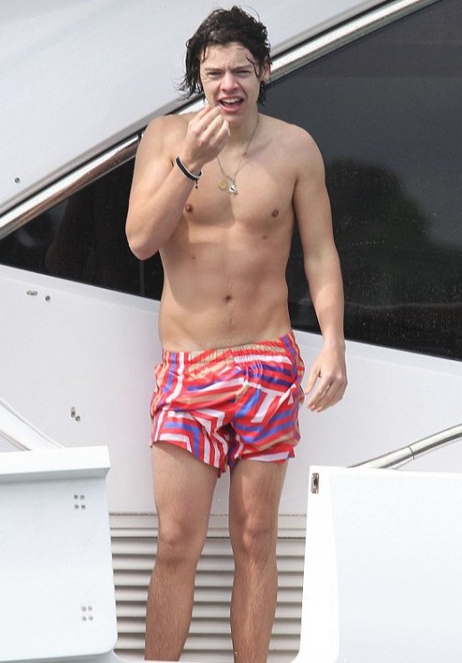 Harry Styles showing off an impressive beach bod while diving off a luxury yacht. He was wearing brightly colored shorts. Afterwards, he and other band mates cooled down with a few Coronas. 