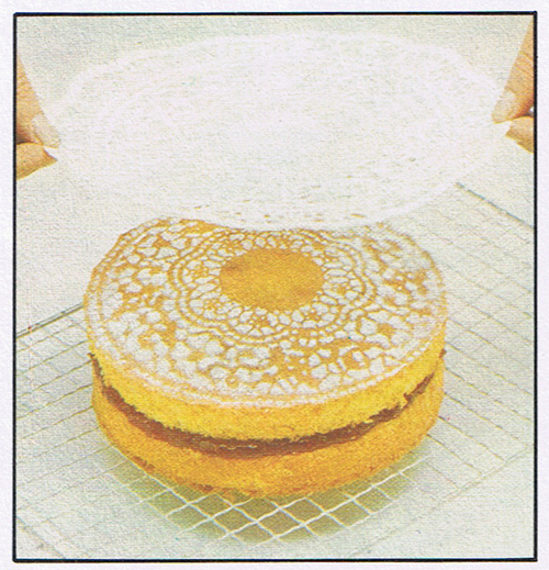 Gently lift the doily off the cake with the tips of your fingers