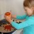 Grace carefully pours the sauce into the pan with the cooked ground turkey.