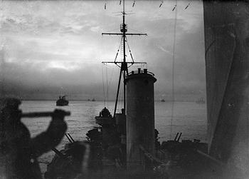 HMS Sheffied as she sails in an Arctic convoy- keeping a steady watch on the merchant ships behind her
