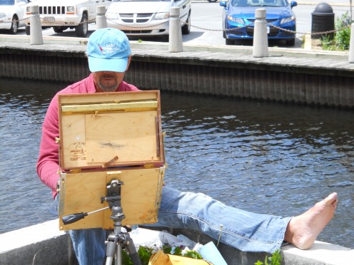 David Diaz casually sitting on a concrete wall as he paints. He almost lost his balance and fell into the water when I asked him to turn his photo around during a heavy gust of wind.