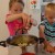 Grace and Alex are having fun putting the vegetables in the pot. Grace and Alex are having fun putting the vegetables in the pot.