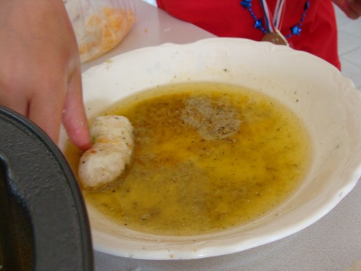 Grace dips the piece of biscuit in the herbed and melted butter.