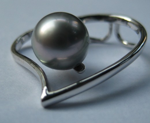 A single 9mm round dark grey Tahitian pearl with muted silvery overtones. The shape and surface and good, the colour and lustre less exciting.  (c) A Jones 2012