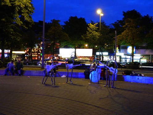 Beatles-Platz at night in Hamburg, Germany. The outline statues of The Beatles stand in a large black-paved circle to resemble a vinyl record at the corner of Reeperbahn and Große Freiheit.