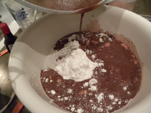 Adding the cooked mixture to the dry ingredients for the cake. 