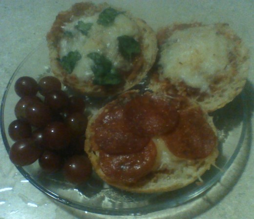 A plate of Enchanting English Muffin Pizzas, served with a bunch of grapes