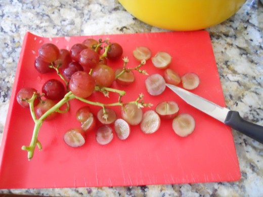 Slice seedless red grapes in half