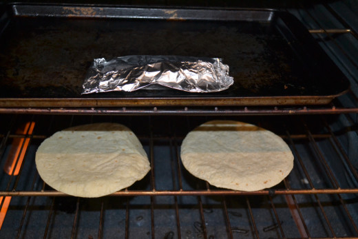 Tilapia wrapped in foil and corn tortillas in oven