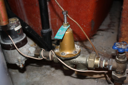 This is a standard water pressure regulator. In my house, it was connected between the main water supply line and the city's water meter. The metal tab sticking out under the lock nut has the valve's specifications.