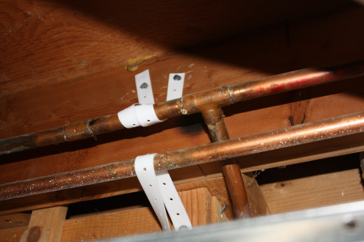 Plastic straps provide a flexible and easy way to secure loose water pipes. Use roofing nails to secure the straps.