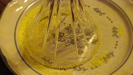 After dipping the mouth of the glass in lemon juice, dip the glass mouth in a plate of coloured sugar.  
