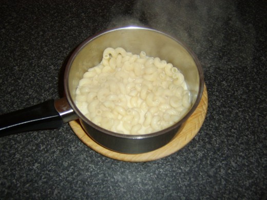 Macaroni is stirred in to cheese sauce
