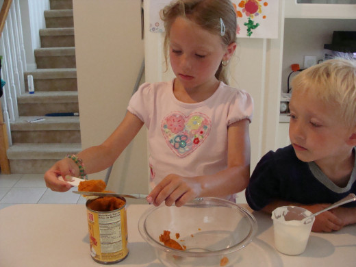 Grace carefully adds the pumpkin puree to the bowl.