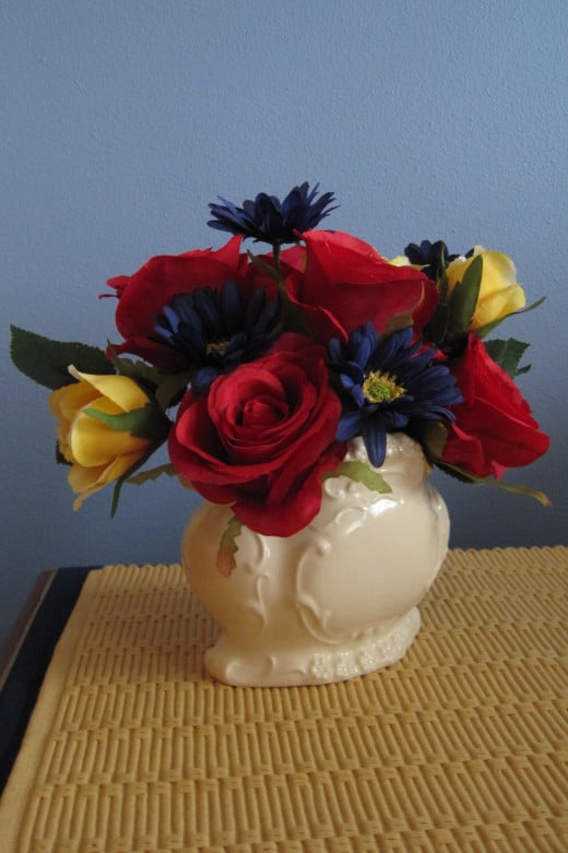 White vintage vase with yellow, red and blue flowers.