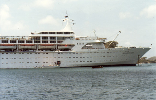Tender leaving the Sun Princess in Grenada harbor in 1980. Note, the tenders/life boats are not covered. Also, no balconies on the cruise ship.