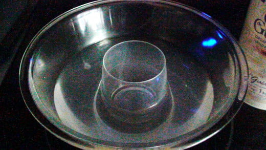Centre the small cup into the large bowl and pour the salt water carefully in the bowl around the small cup.