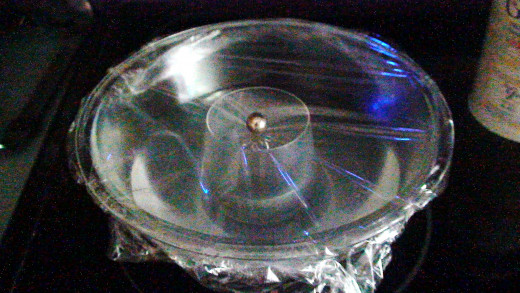 Put the plastic wrap on the bowl and press against the rim of the bowl.  Place a weight, in this case a steel ball, in the centre over the small glass.