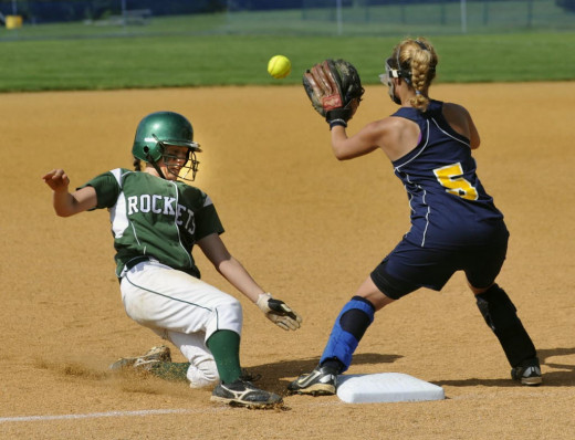 This third baseman is wearing a mask, which is not typical for infielders except the pitcher. But this picture shows the danger of standing in front of base. If the runner used the legs instead, it would have went into the girl's ankle.