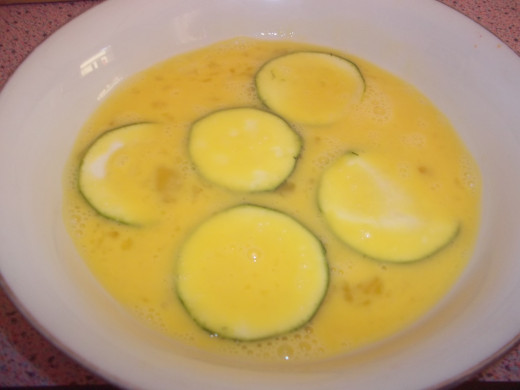 Dipping the zucchini in egg. 