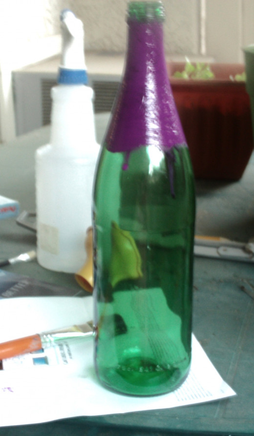 Here I am painting the top part of the green glass bottle with purple water based paint.