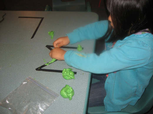 Tape letters help a child make playdough letters.