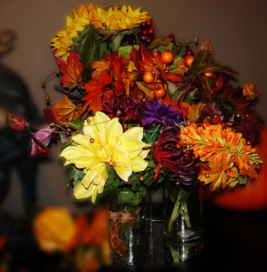 A very simple table center for a fall wedding created from three separate bunches of flowers added to three separate vases all the same width, but different heights. The three vases are placed together and gold beaded wire trailed over the result. 