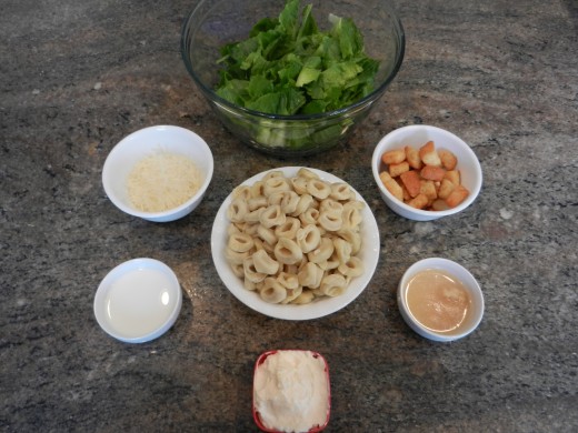 Ingredients for tortellini salad. Garlic and lemon juice are in the same bowl. 