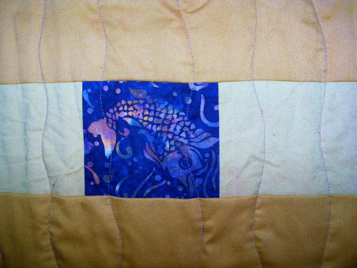 I added a small fish cut fussy cut from a bigger piece of fabric to add interest to this otherwise boring pieced backing.