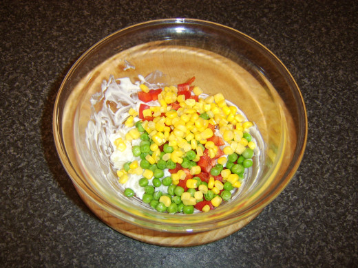 Sweetcorn, peas and diced red pepper are stirred in to potato salad with seasoning