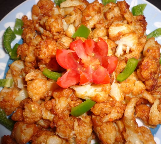 Fried Cauliflower or Gobi chilli garnished with Tomato & Capsicum