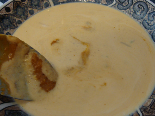 Tempering the cream to the pumpkin soup.