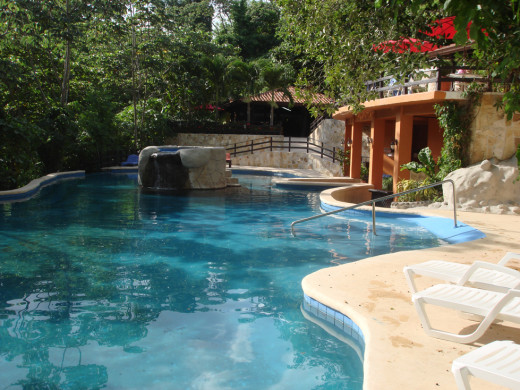 A view of the pool towards the restaurant at Vandara.  There is a jacuzzi in the center that you climb up to and a bar is in the center.